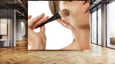 A young woman applied liquid foundation on her face with a brush Wall mural