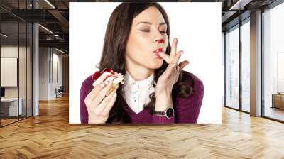 Beautiful stained girl eating cake and licks her fingers Wall mural