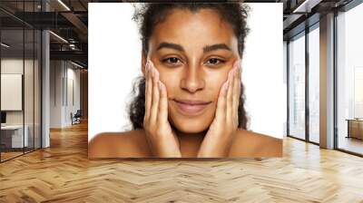 portrait of a happy young dark-skinned woman applying cream on her face on a white background Wall mural