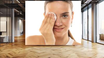 Portrait of a young smiling woman removing her make-up on a white background Wall mural