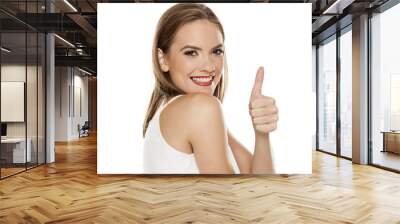 Portrait of young beautiful woman with makeup on white backgeound and showing thumbs up Wall mural