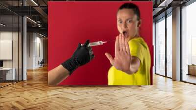 Woman refuses to receive the vaccine on a red background Wall mural