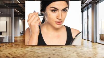 young freckled woman applying liquid foundation with makeup brush Wall mural