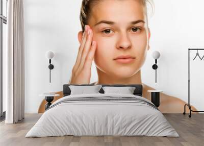 Young woman tightening  her face skin with the fingers on white background Wall mural