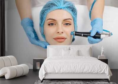 A cosmetologist wearing gloves performs vacuum cleaning and polishing of the facial skin of a middle-aged woman in a cosmetology clinic. Professional moisturizing and rejuvenating hardware procedures. Wall mural