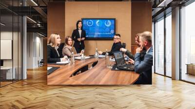 A diverse multinational team of professional business people meet in the conference room of a modern office. Creative team at the table discussing data analysis and planning a marketing campaign Wall mural