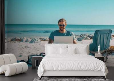 A man sitting on the beach with his laptop, working as an online marketing expert for travel enthusiasts and nomads Wall mural