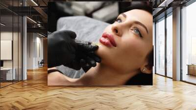 Close-up, woman's lips. A surgeon wearing medical gloves carefully and slowly injects hyaluronic acid into a woman's lips using a syringe. lip augmentation procedure. beauty injections. Plastic surger Wall mural