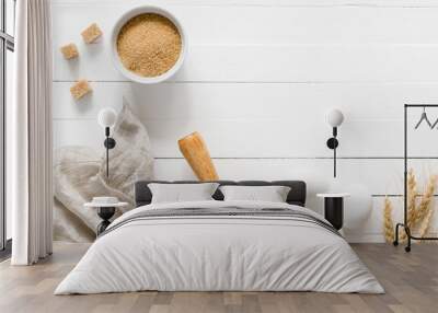 Baking ingredients: brown sugar, white eggs, rolling pin, and wheat on white wooden table. Top view, copy space Wall mural