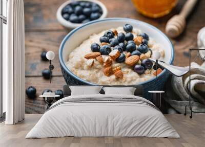 Oatmeal porridge with blueberries, almonds in bowl on wooden table background. Healthy breakfast food Wall mural