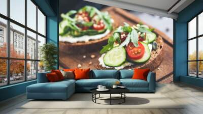 Rye bread with cream cheese and cucumber toast garnished with cherry tomato, arugula leaf and seeds. Healthy snack, clean eating. Closeup view, selective focus Wall mural