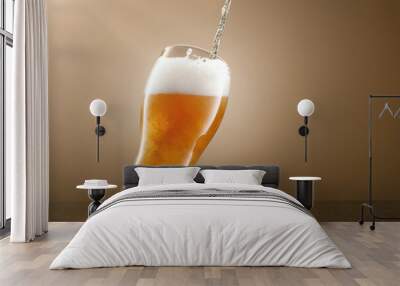 Stream of draught beer in glass on a beige background. Pouring lager beer in a glass. Glass of fresh and cold light beer. Selective focus Wall mural