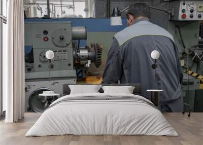 Turner worker is working on a lathe machine in a factory. Wall mural