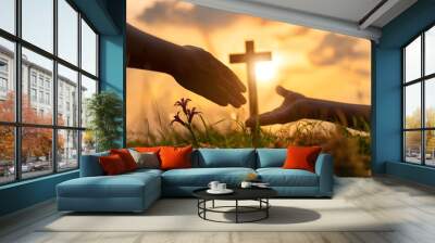 A hand is outstretched symbolizing offer of help to another at sunrise, cross silhouette in the background, power of religion, moment of spiritual connection in nature, banner with copyspace for text. Wall mural