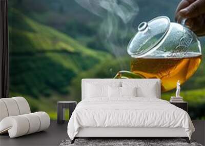 glass teapot pours hot tea into transparent cup on wooden table with fresh leaves on tea plantation, Wall mural