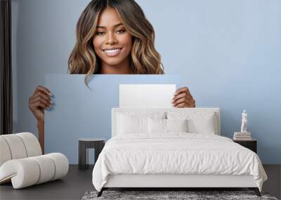 Black woman holding white sign paper in her hands and smiling at the camera with blue background.Minimalism.Creative designer fashion glamour art. Wall mural