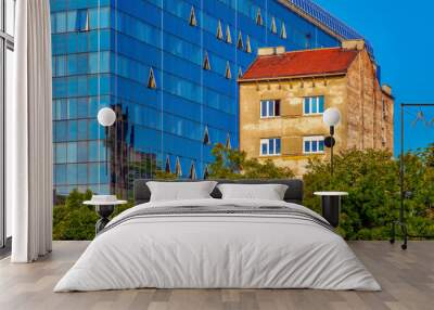 View of an old aged building standing next to a new modern with a glass facade. Image Wall mural