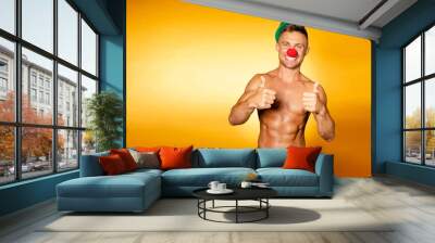 Young attractive clown man with beautiful body. Orange background. Wall mural