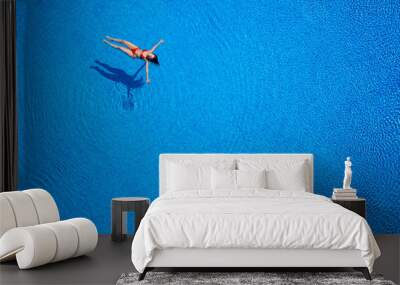 View from the top as a woman in a red swimsuit lying on her back in the pool. Relaxing concept Wall mural