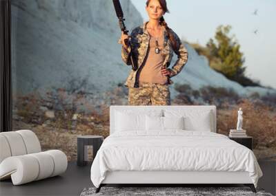 Young female soldier dressed in a camouflage with a gun in the l Wall mural