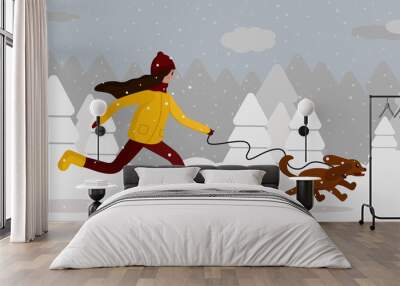 Running girl behind a dog on a background of a snowy forest. Girl in a yellow jacket and cocker spaniel on a background of snow and Christmas trees. Wall mural