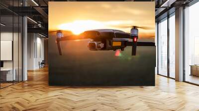 unmanned quadcopter in flight with a digital camera at sunset. drone silhouette at sunset Wall mural