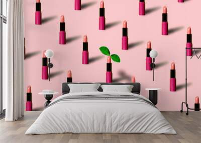 Pattern made with many red lipsticks on pink pastel backdrop. One lipstick with green leaf. Minimal luxury makeup cosmetic concept with trendy summer shadows. Flat lay, top view background. Wall mural