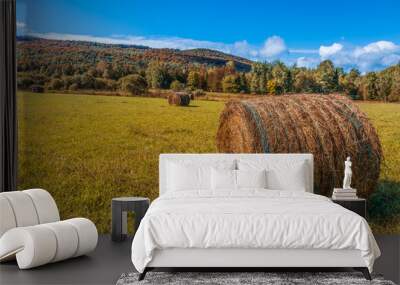 Haystack rolls on gold agriculture field. Beautiful field haystack rolls in autumn season. Haystacks harvest in fall landscape. Amazing view with rolled hay stacks in autumnal season. Wall mural