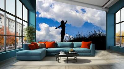 Silhouette young woman open arms on hill Wall mural