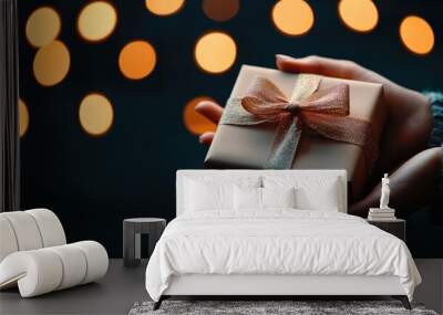 Hand holding a beautifully wrapped gift box with festive bokeh background. Wall mural