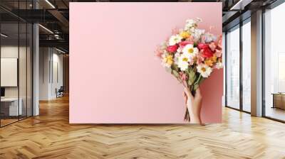 Flower bouquet in woman hand on pastel wall background. Top view. Wall mural