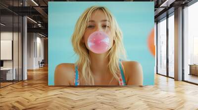 Casual blond woman blowing pink bubble gum balloon Wall mural