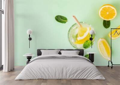 Ice lemon water or lemonade with mint on a green background. A glass of fresh fruit drink for summer heat. Wall mural