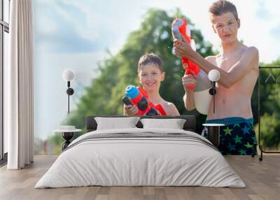 Two Kids playing with water guns outdoors. Cute boys spraying water from a gun in backyard. Wall mural