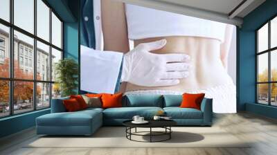 Doctor and patient. Physician wearing white medical gloves examining back of female patient in clinic. Orthopedics and pediatric in medicine Wall mural