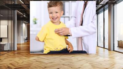 Happy little boy having fun while is being examine by doctor by stethoscope. Health care, insurance and help concept Wall mural