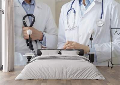 Two doctors wearing white coats and stethoscopes, using a digital tablet, discussing a patient's medical history. Medicine and science Wall mural