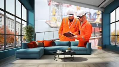 Two sailors in orange overalls work on the ship with documents. Wall mural