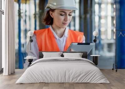 Female construction engineer. Architect with a tablet computer at a construction site. Young Woman looking, building site place on background. Construction concept Wall mural