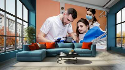 The dentist shows the patient a picture of the result of treatment. Satisfied patient Wall mural