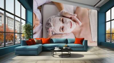 Woman in moisturizing anti-wrinkle mask. A woman is lying down, resting in a beauty salon. SPA procedures at home or in a cosmetology center. Wall mural