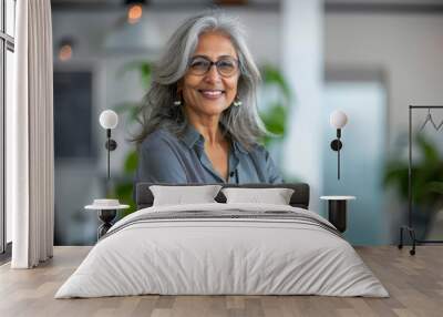 A smiling, happy, and confident Indian old mature professional business woman, a corporate leader and senior middle-aged female executive, stands in her office with arms crossed, projecting confidence Wall mural