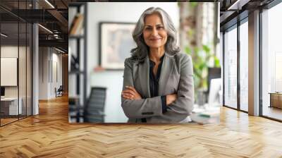 A smiling, happy, and confident Indian old mature professional business woman, a corporate leader and senior middle-aged female executive, stands in her office with arms crossed, projecting confidence Wall mural