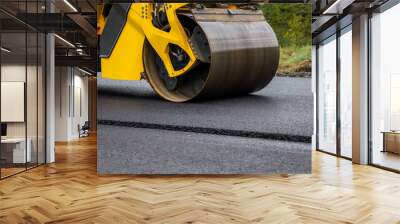 Asphalt road roller with heavy vibration roller compactor press new hot asphalt on the roadway on a road construction site. Heavy Vibration roller at asphalt pavement working. Repairing. Wall mural