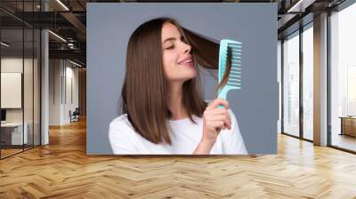 Attractive woman combing hair. Beautiful girl combs hair. Haircare concept. Wall mural