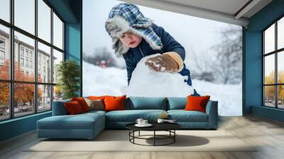 Beauty Winter child with snowman in frosty winter Park. Winter children in frosty winter Park. Portrait of little boy child in snow Garden make big snowball. Wall mural