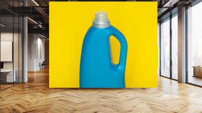 Blue plastic bottle stands on yellow background. Conditioner or liquid powder for washing. Capacity with space for copying. Layout for logo application. Wall mural