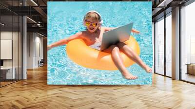 Child with laptop in swimming pool in summer day. Summer business and online technology. Wall mural