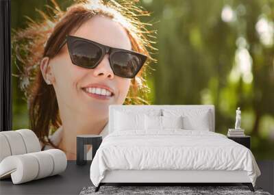 Close up head portrait of smiling caucasian woman with white teeth wear sunglasses. Perfect healthy smile with veneer. Skin and dental care. Nature green background. Wall mural