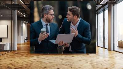 Excited suprised two business teams men team using tablet laptop outdoor. Business men team working on laptop outdoor. Businessmen looking laptop with their business success in city. Business success. Wall mural